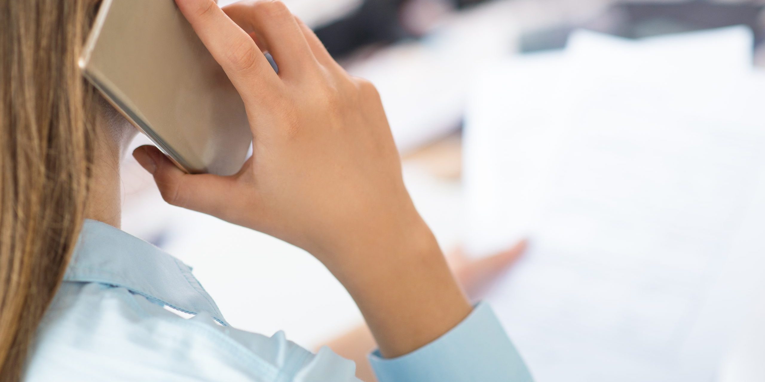 Closeup of woman talking on smartphone and holding papers