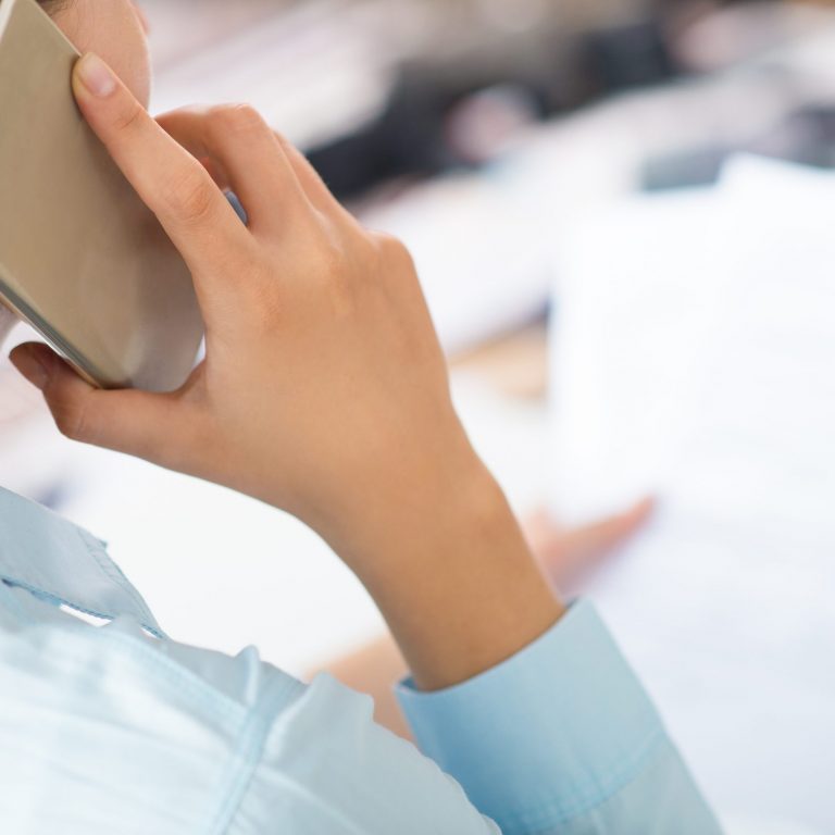 Closeup of woman talking on smartphone and holding papers